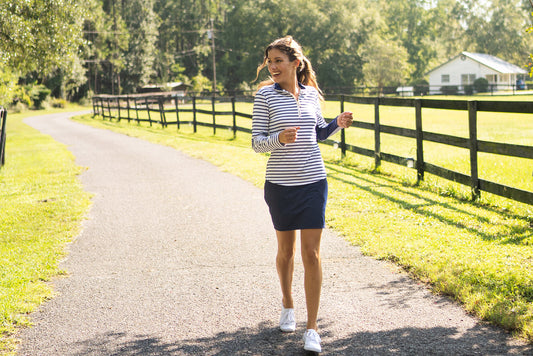 Woman wearing Navy Stripe Sport Zip Polo & Navy Longer Skort running