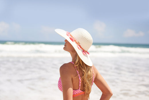 Woman wearing Cabana Life Boca Raton Reversible Bikini Top and hat on beach facing ocean