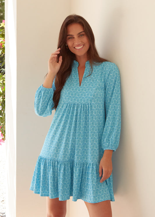A brunette woman wearing the Cabana Life sun protective Rosebay Relaxed Dress against a wall.