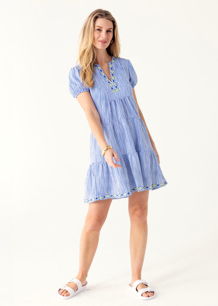 A blonde woman wearing the Cabana Life sun protective Seaside Embroidered Short Sleeve Tiered Dress in a studio.