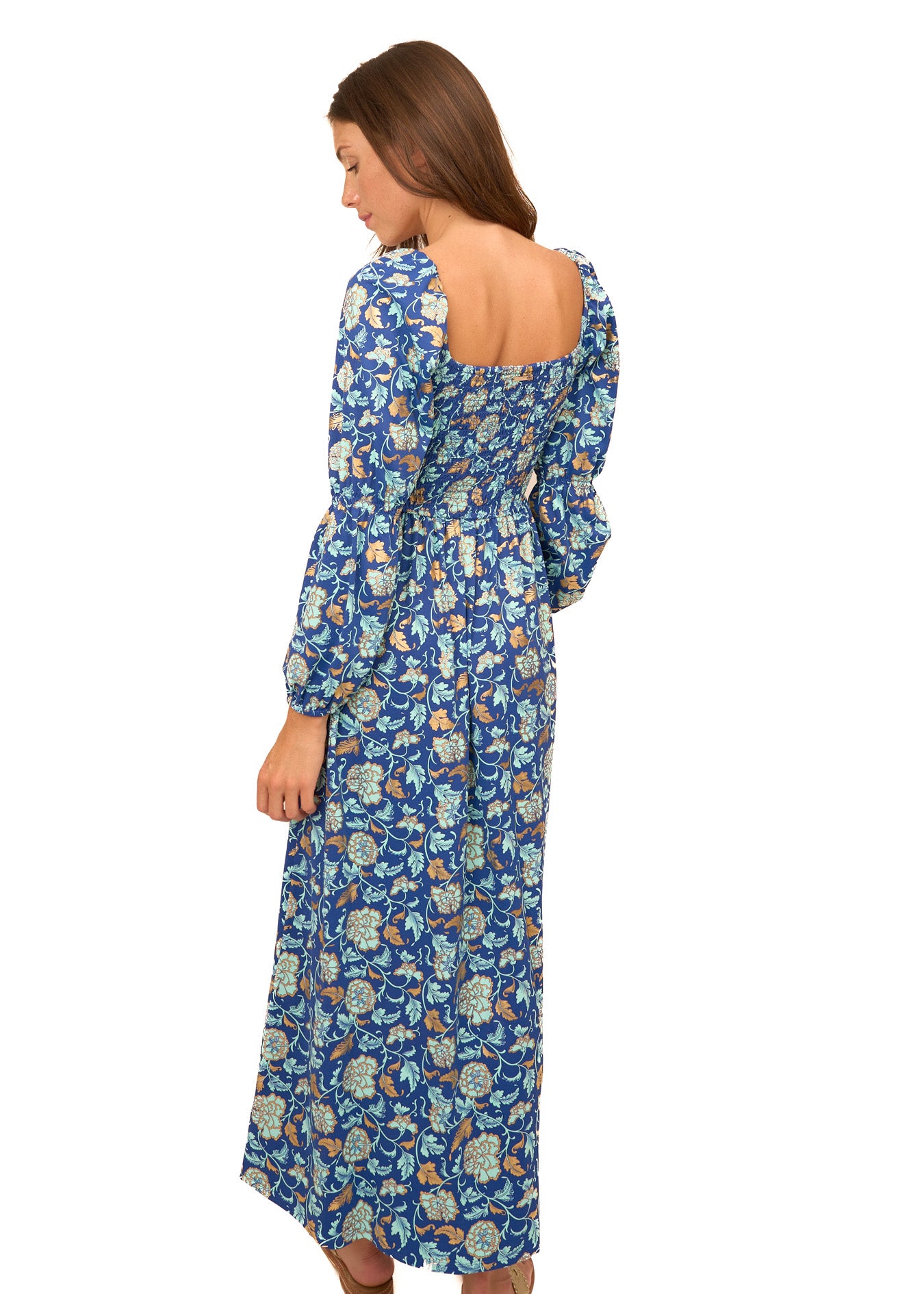 The back of a brunette woman wearing Cabana Life's sun protective Navy Floral Metallic Puff Sleeve Maxi Dress on a white background.