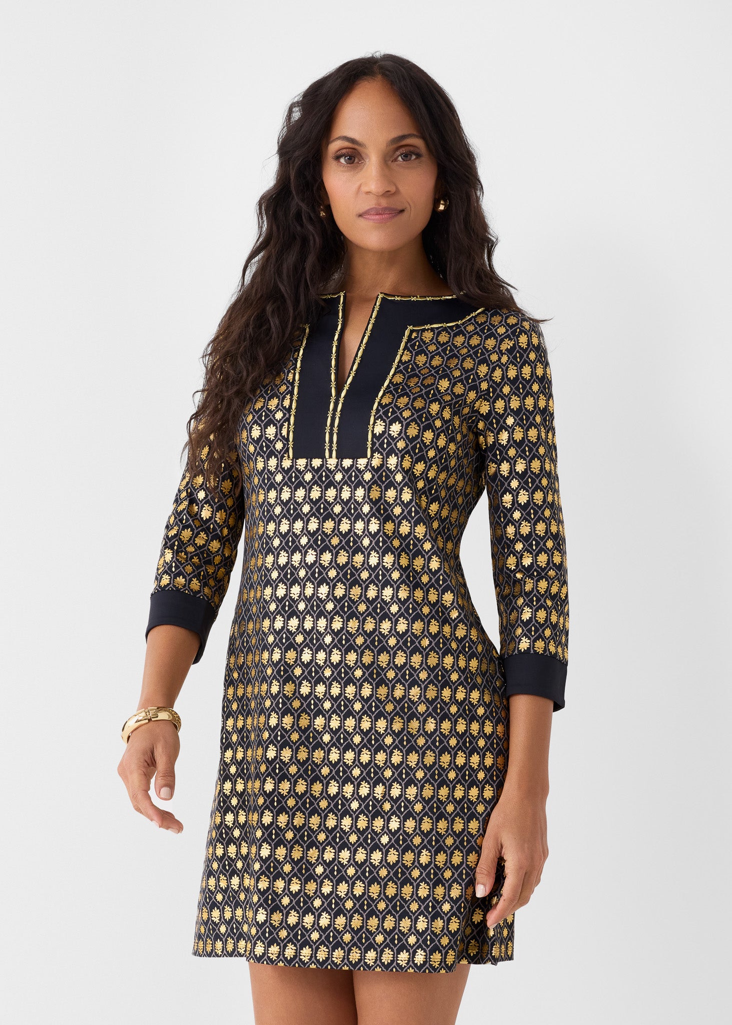 Woman wearing a black and gold patterned dress on a white background