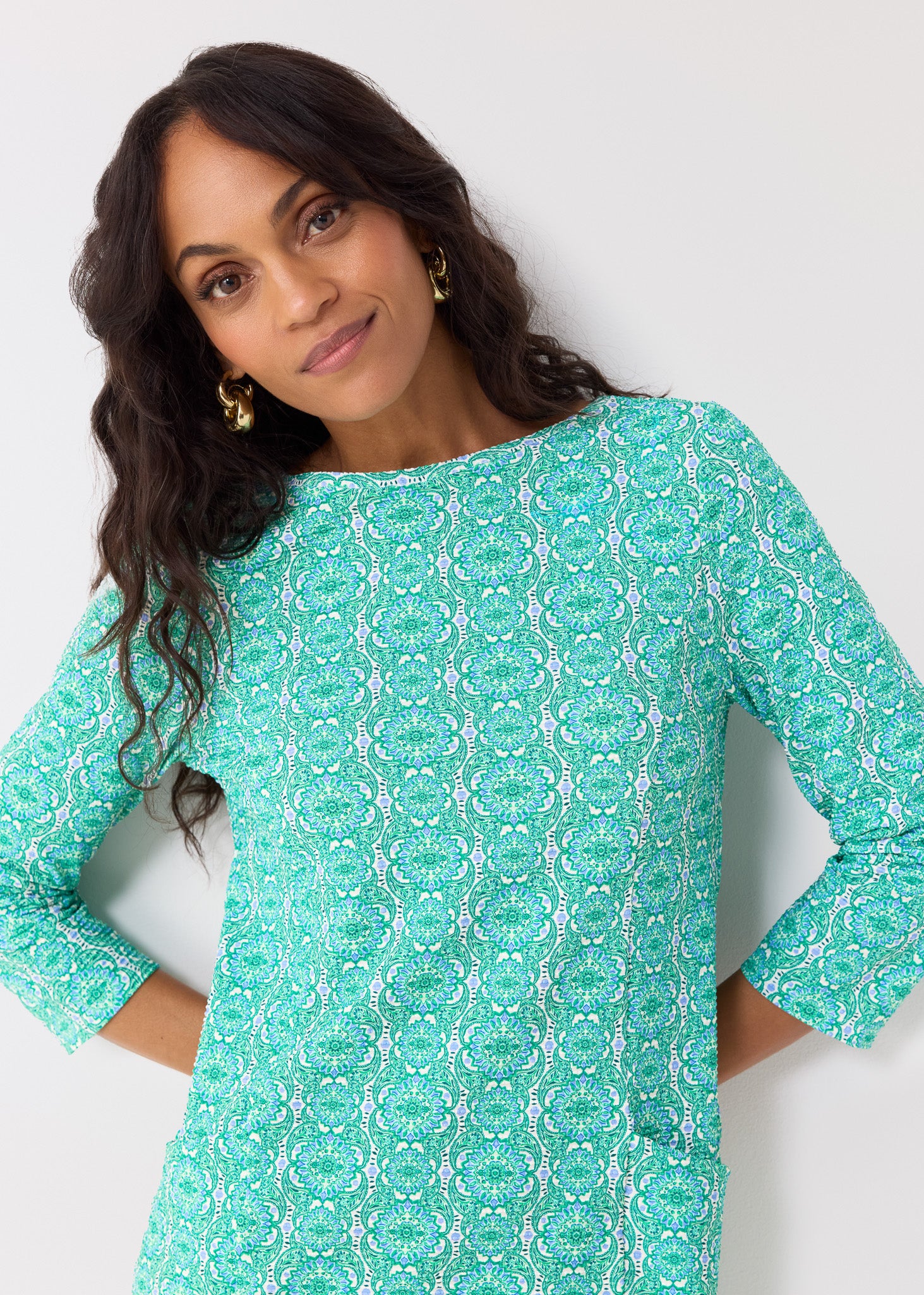 Woman wearing a teal patterned dress against a white background