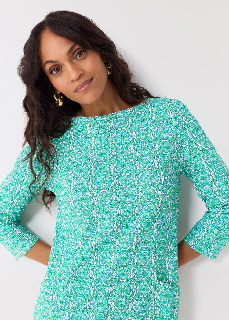 Woman wearing a teal patterned dress against a white background