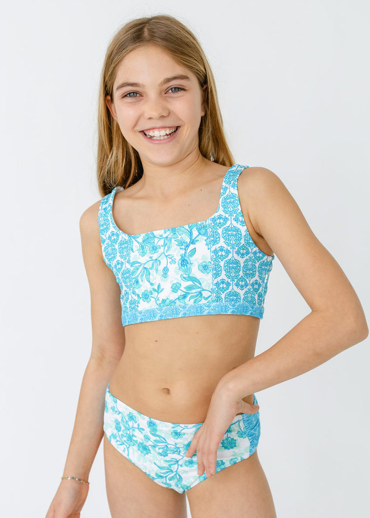 A blonde girl wearing the bikini from Cabana Life's sun safe Girls Rosebay 3-Piece Short Sleeve Rashguard Set.