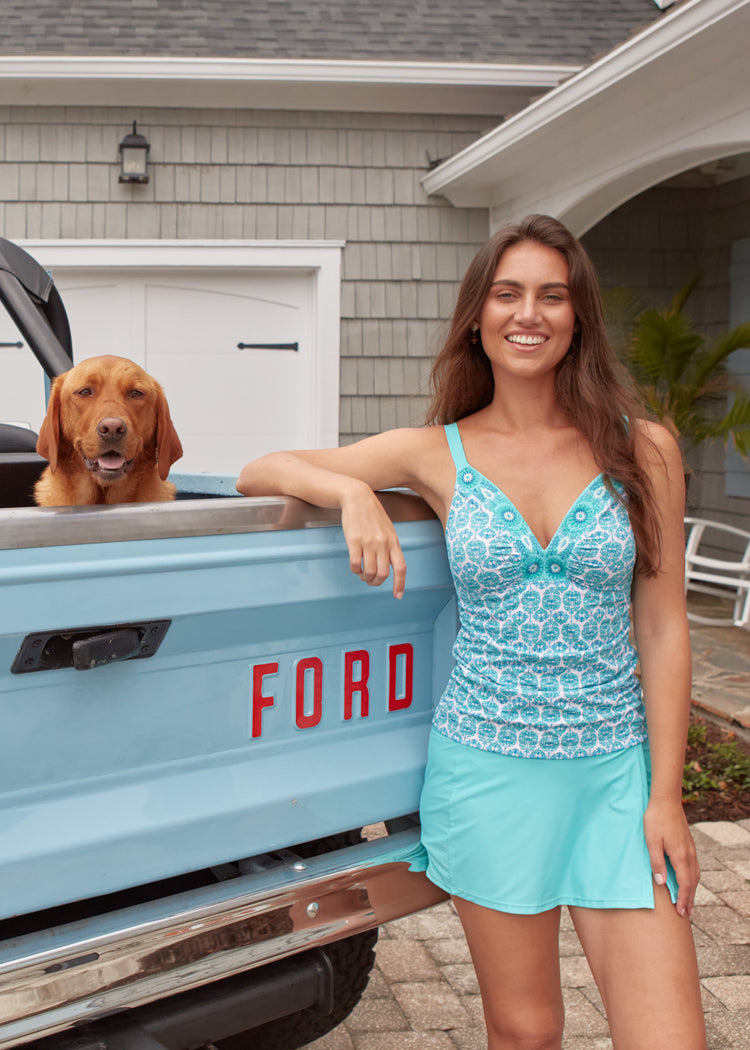 A brunette woman wearing the Cabana Life sun protective Rosebay Embroidered Tankini Top by a blue Ford Bronco.