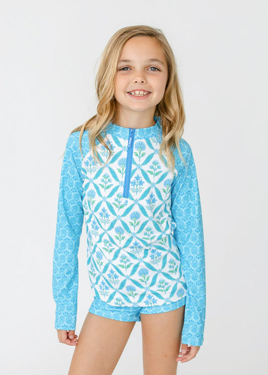 A blonde girl wears Cabana Life's sun safe Girls Rosebay 3-Piece Long Sleeve Rashguard Set.
