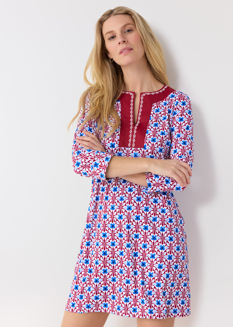 Woman wearing a patterned dress with red, white, and blue design on a plain background