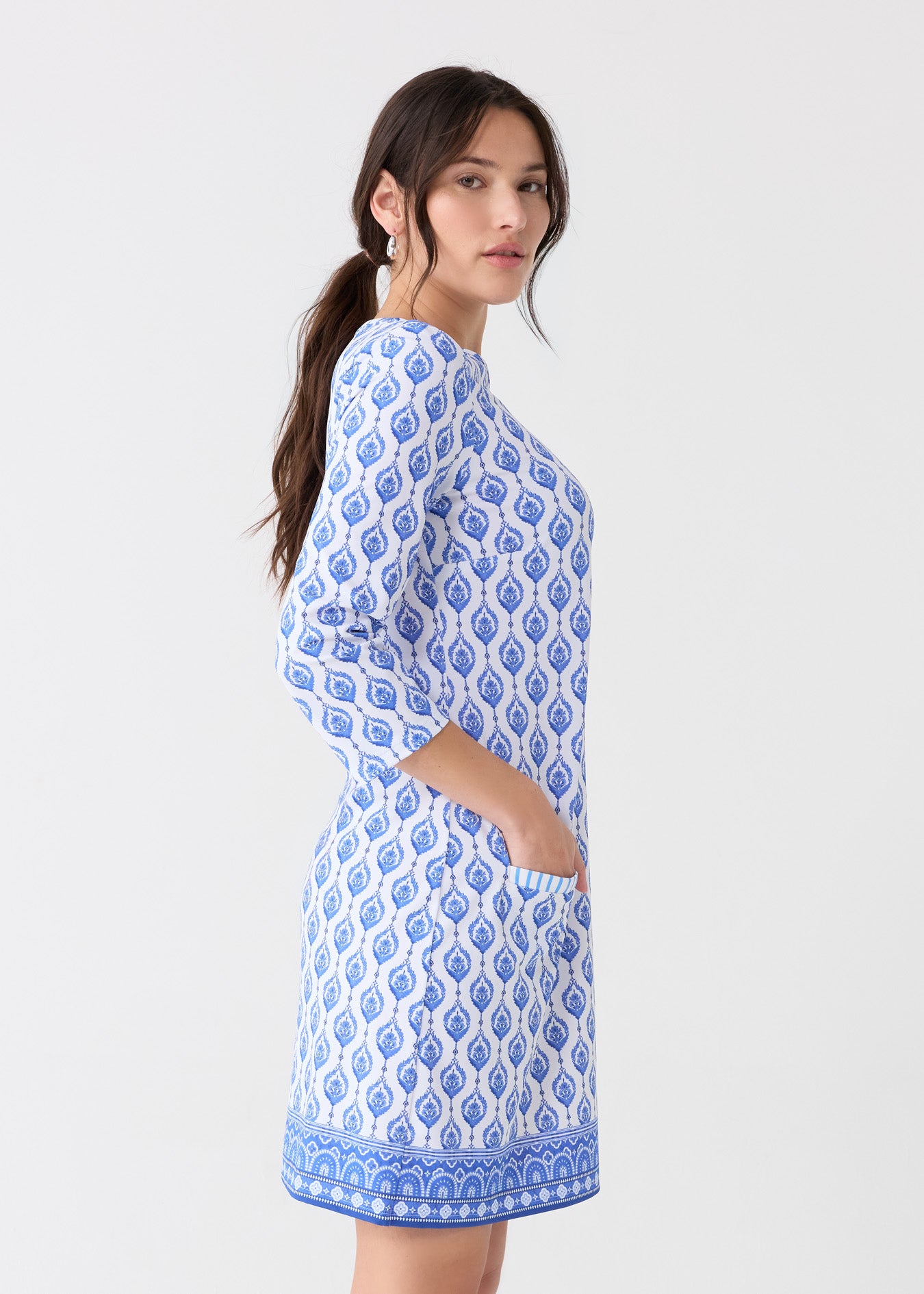 The side of a brunette woman wearing the Cabana Life sun protective Palm Beach Cabana Shift Dress with a hand in the front pocket.