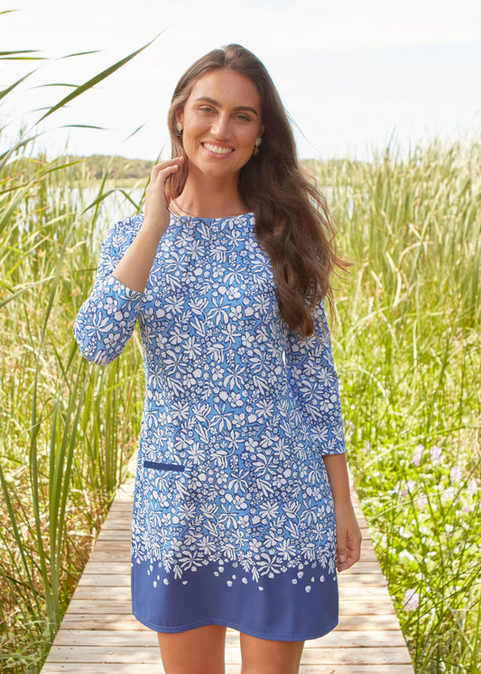 Woman in a blue floral dress standing on a wooden path in a natural setting