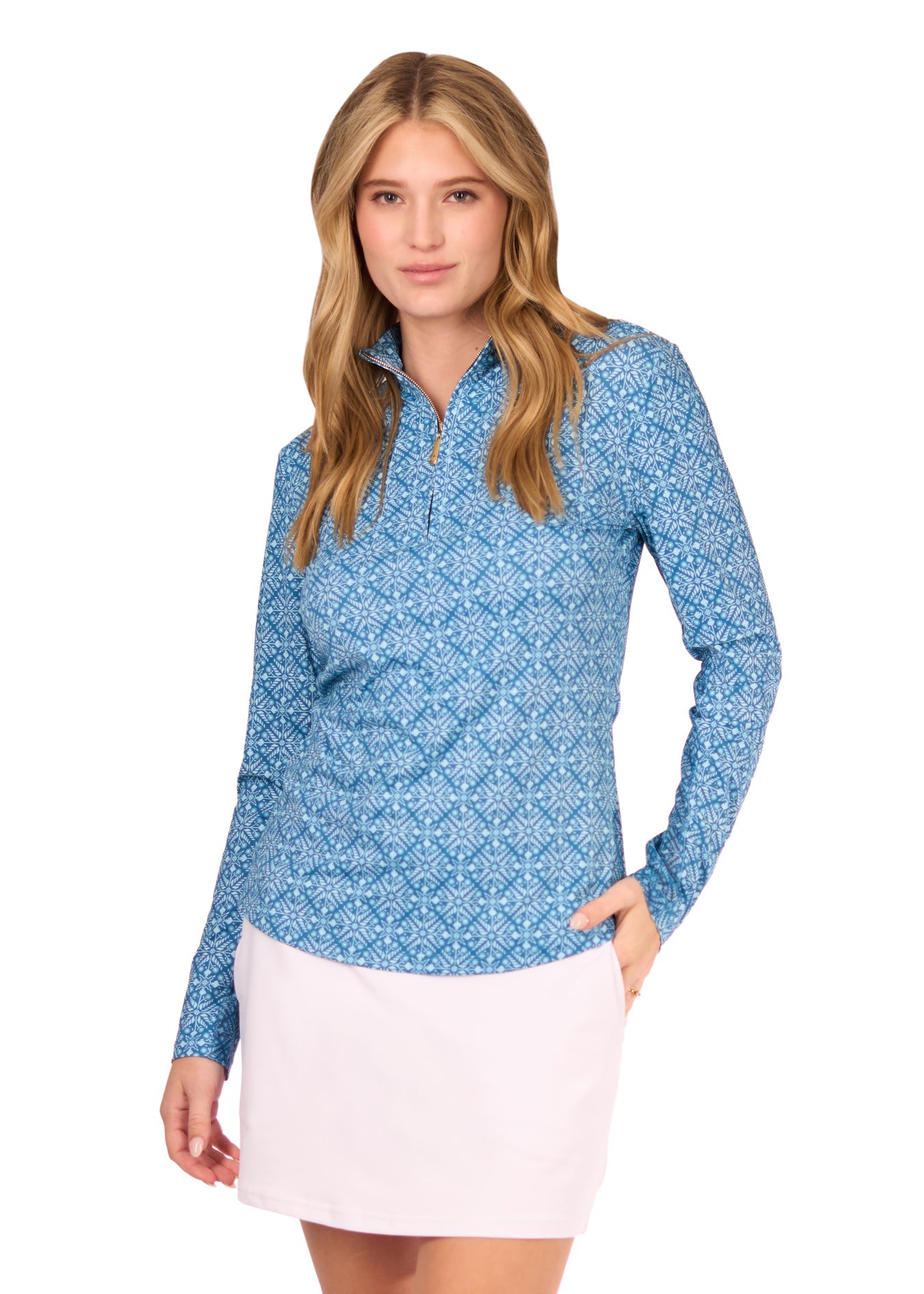 A blonde woman wearing the sun protective & turquoise patterned Camden 1/4 Zip Sport Top and White 14" Skort from Cabana Life on a white background.