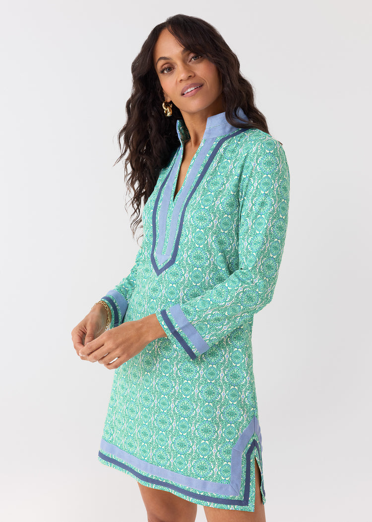Woman wearing a green patterned dress with blue accents on a white background