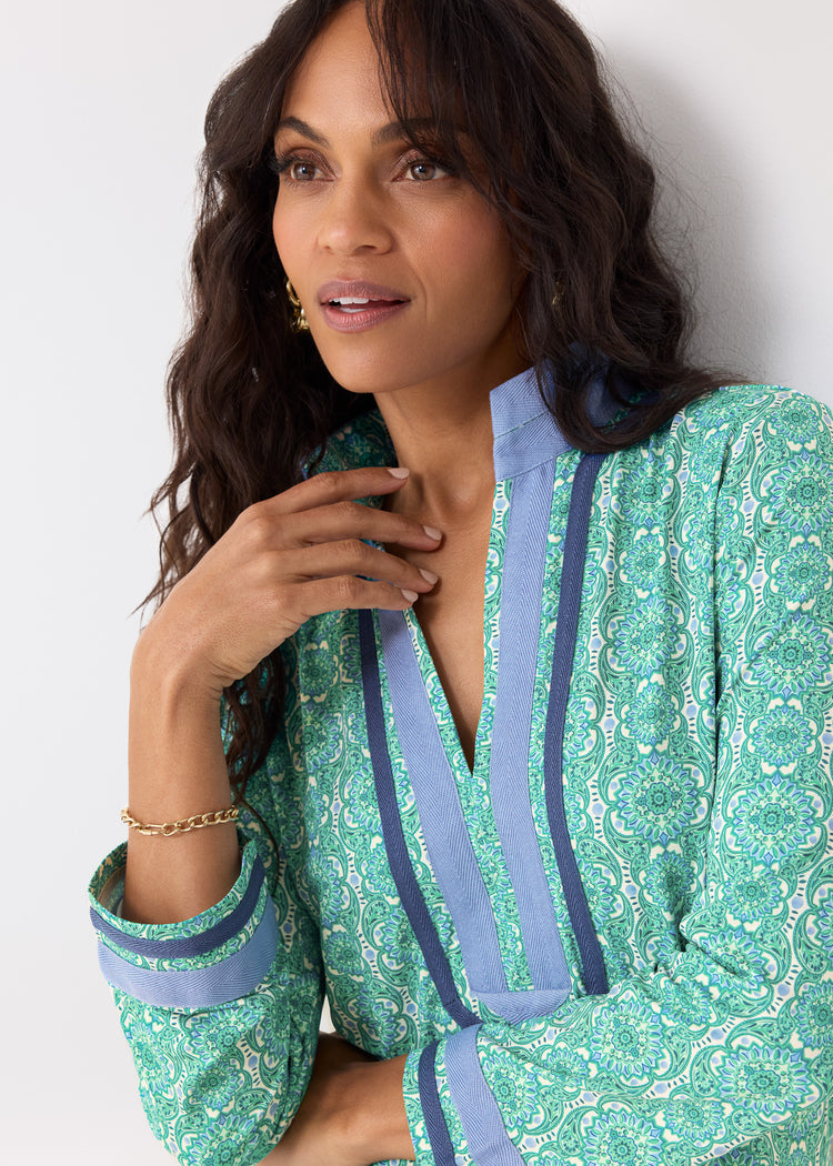 Woman wearing a green and blue patterned outfit against a white background
