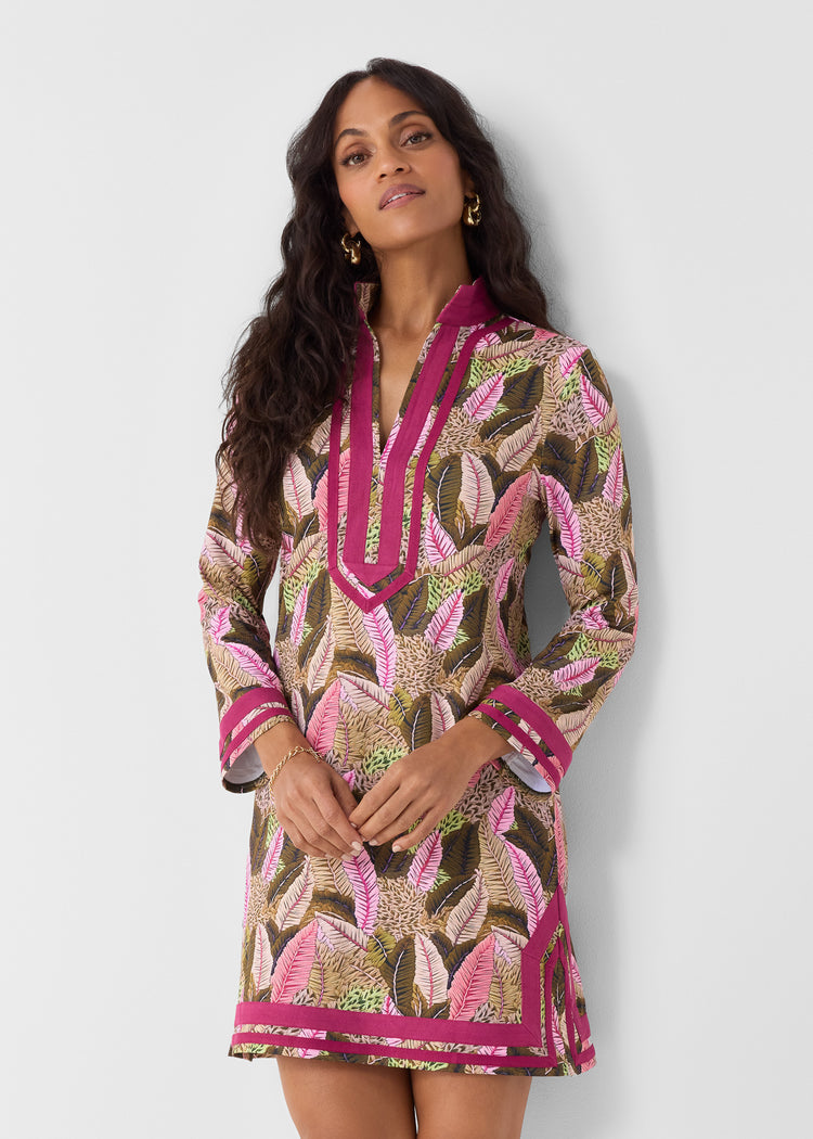 Woman wearing a patterned dress with pink accents against a white background