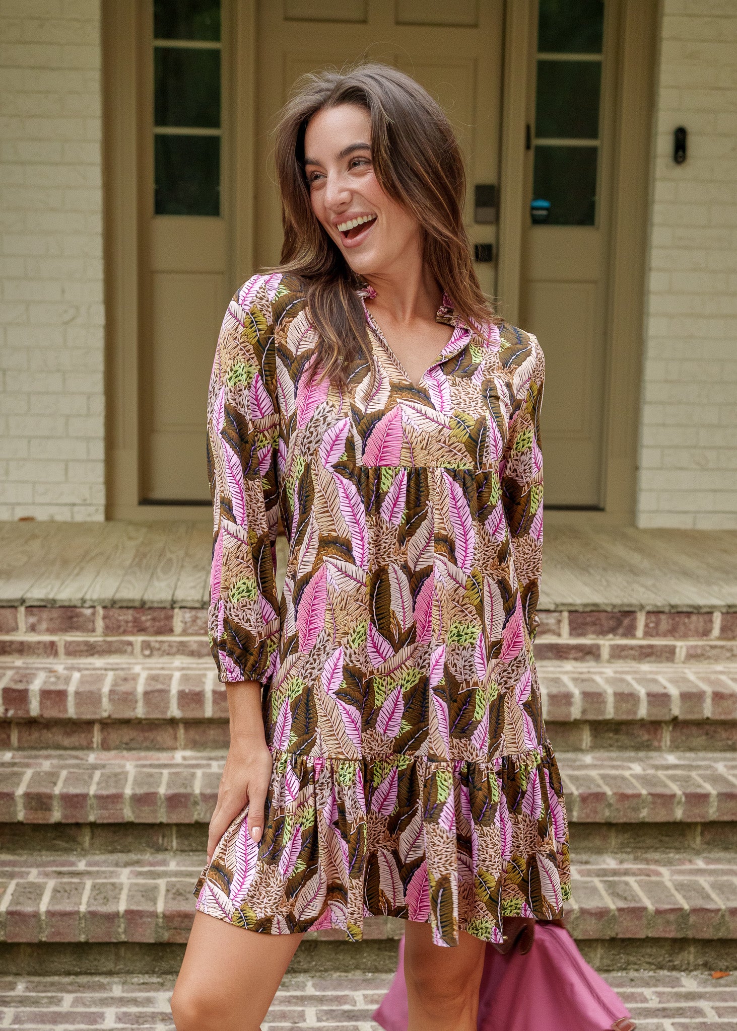 Woman wearing a patterned dress standing on a porch.