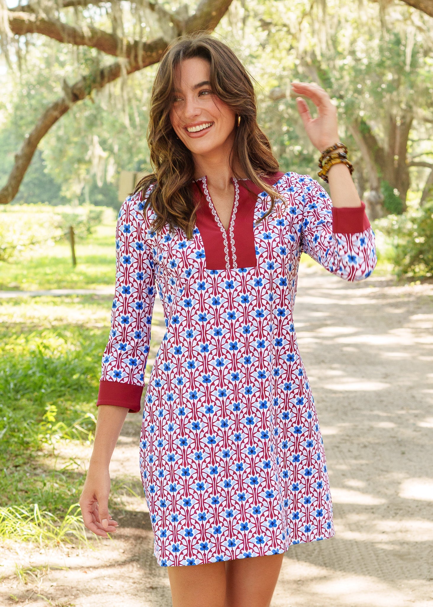 Woman wearing a patterned dress with red, white, and blue colors in a park setting.