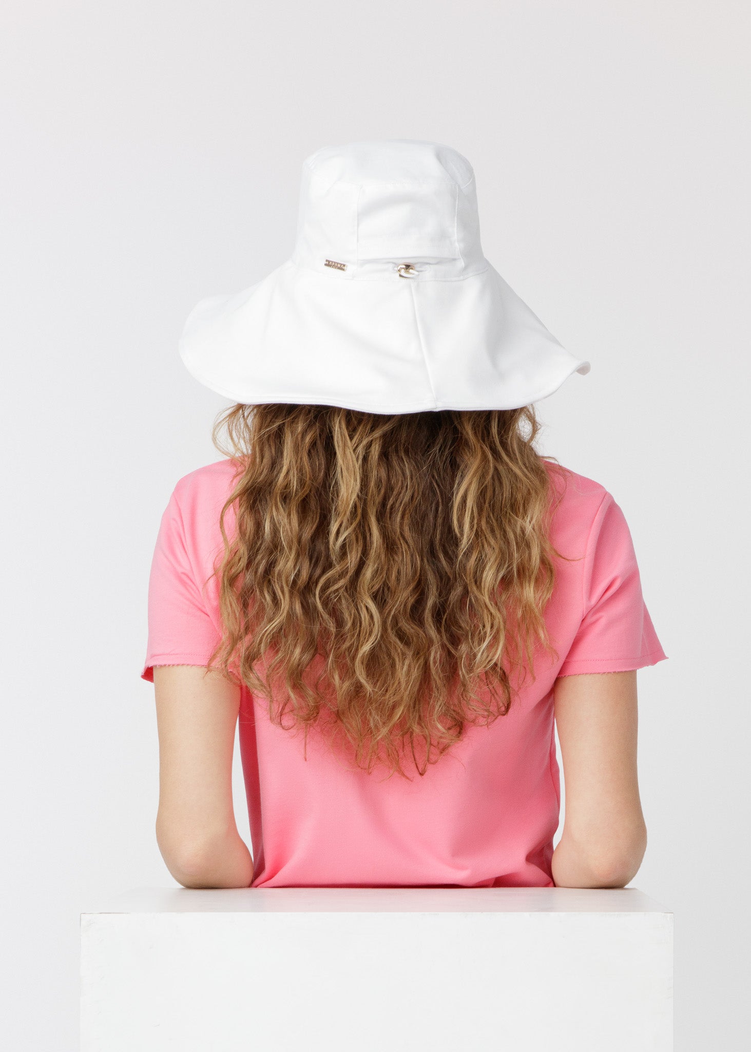 Brunette woman wearing our UPF 50+ White Reversible Wide Brim Sun Hat showing the back of the hat.