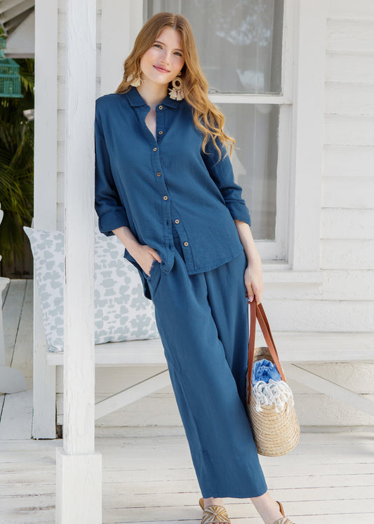 Woman in a blue outfit standing on a wooden deck.