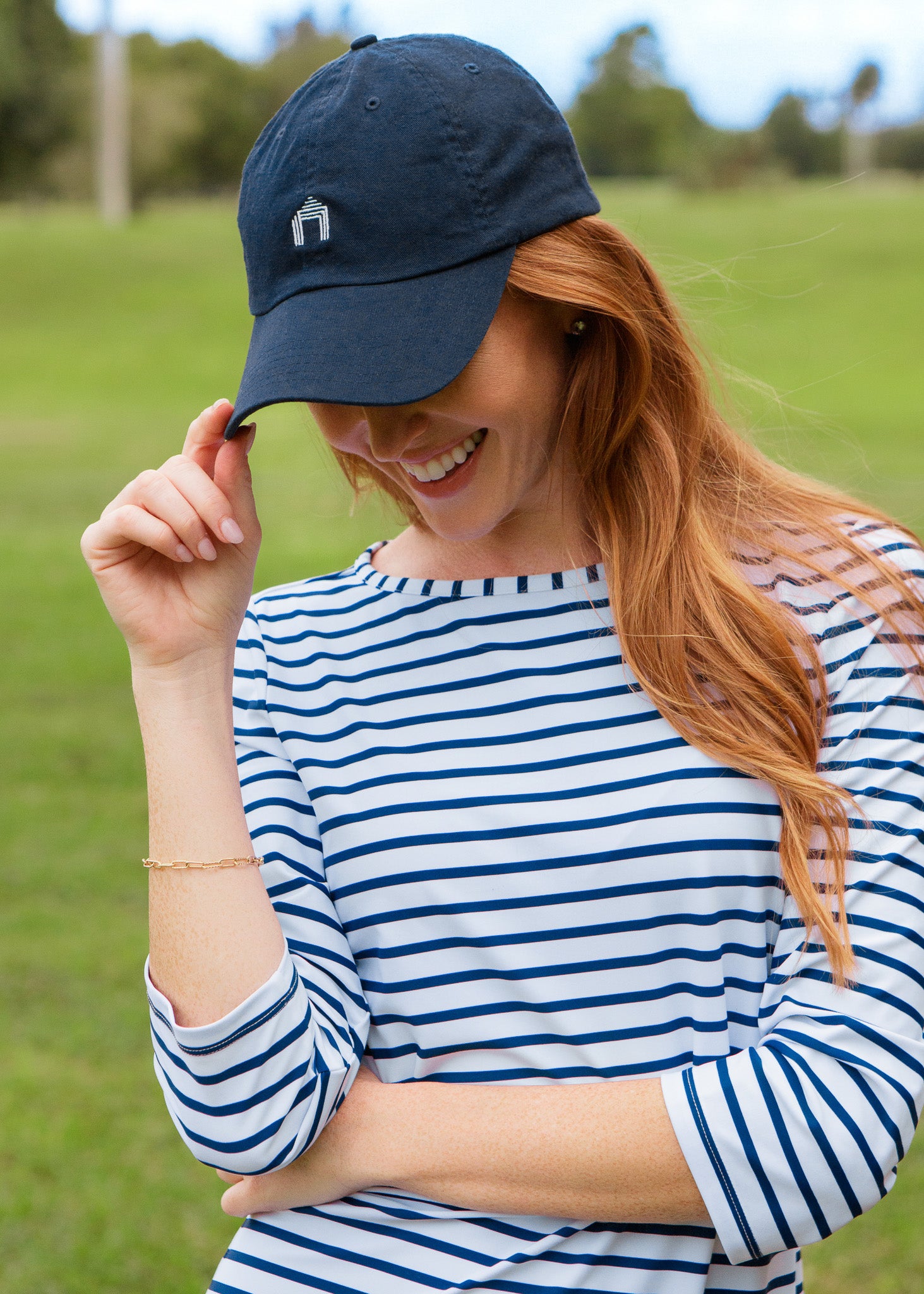 Woman wearing a navy cap and blue and white striped dress outdoors