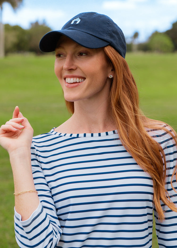 Woman wearing a blue and white striped dress and navy cap outdoors