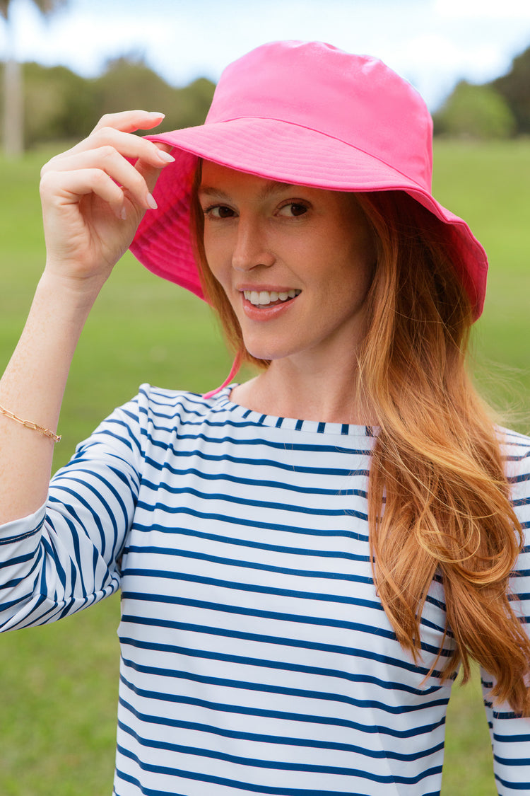 Woman wearing a pink hat and dress shirt outdoors