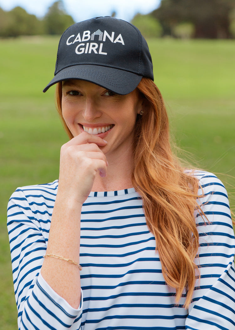 Woman wearing a navy cap with 'CABANA GIRL' text in an outdoor setting
