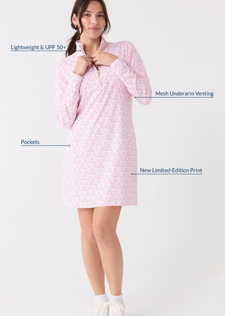 A brunette woman touching the collar of the Cabana Life sun protective Golf 1/4 Zip Sport Dress and wearing white sneakers and socks.