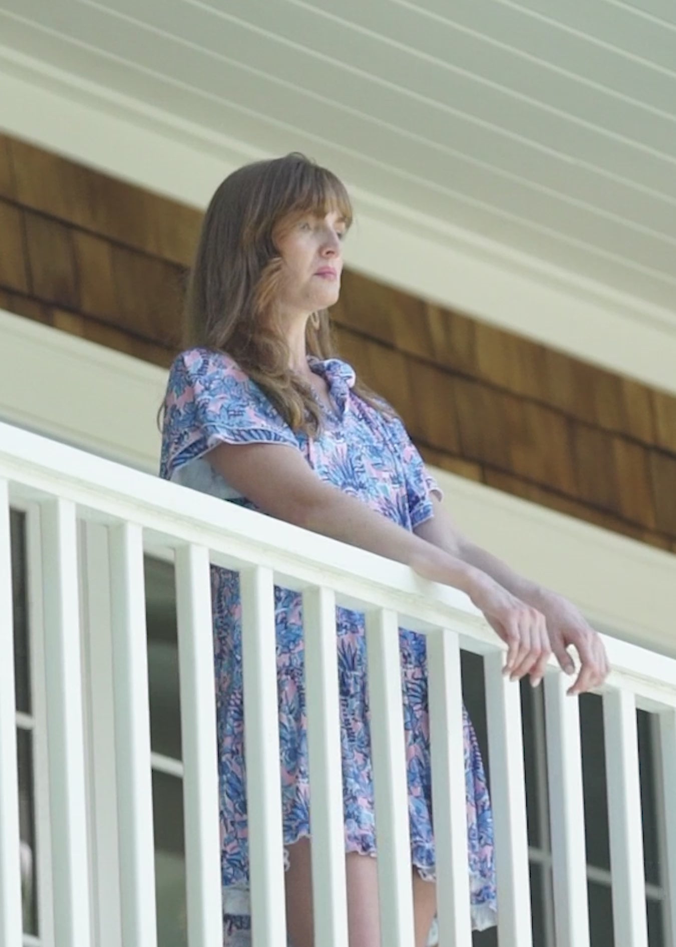 A redhead woman wearing the Cabana Life sun safe Palm Beach Short Sleeve Tiered Dress on balcony with other women.
