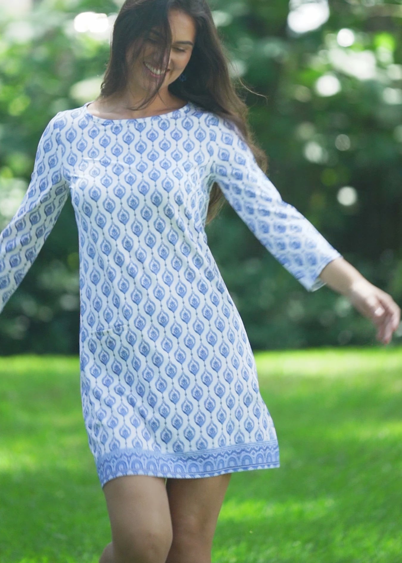 A brunette woman wearing the Cabana Life sun protective Palm Beach Cabana Shift Dress outside.