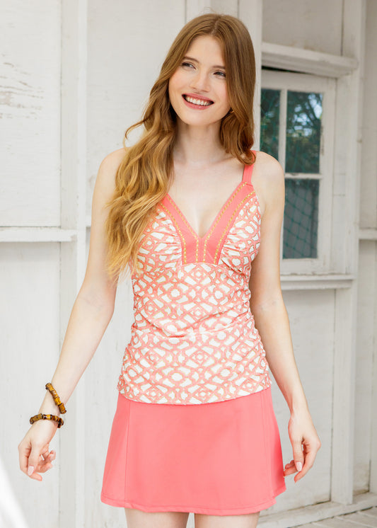 Woman wearing a pink patterned top and skirt standing in front of a white wooden door.