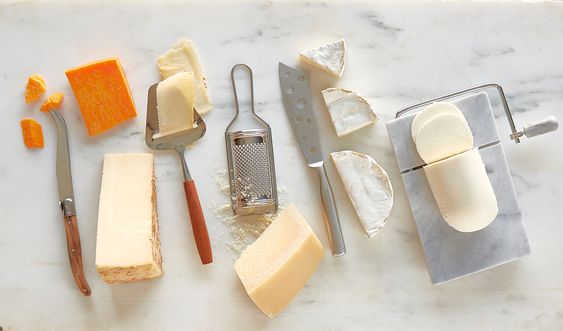 Cheese knives and cheese on white marble