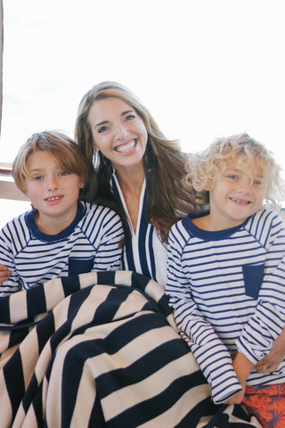 Two boys wearing Red Crab Swim Shorts and Rashguard set on either side of woman wearing White/Navy Trim Terry Tunic