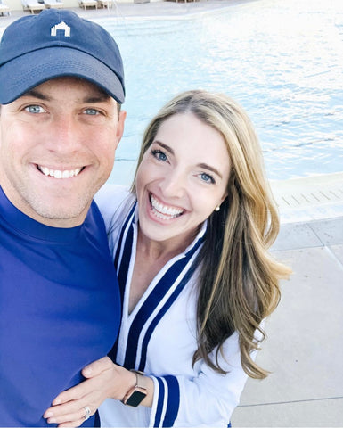 Man wearing Cabana Life Navy baseball hat and Men's Navy Rashguard with Woman wearing White/Navy Trim Terry Tunic