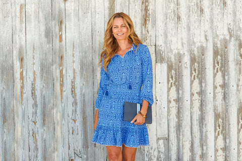 Woman wearing Boston Ruffle Dress with bag against wood wall