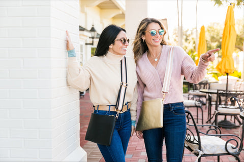 Women in sweaters with jeans and crossbody bags