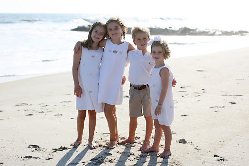Four kids wearing white on beach