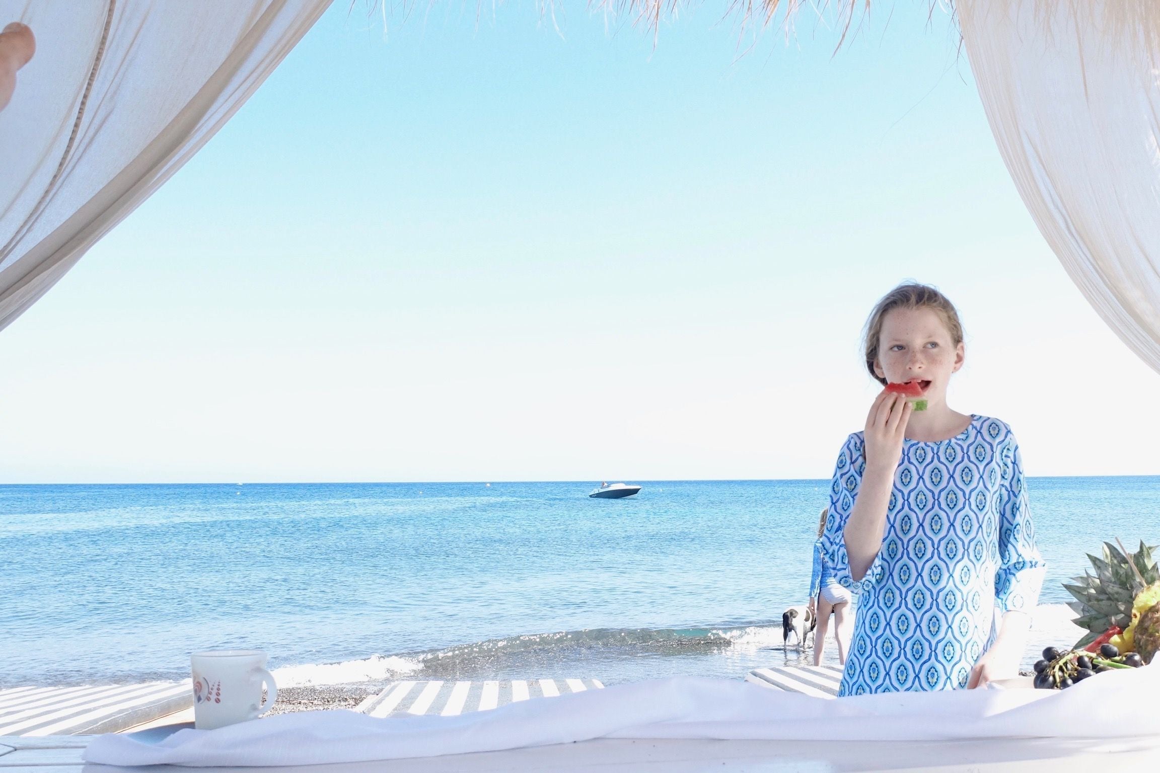 Girl eating watermelon under cabana on beach in Santorini