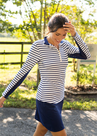 Woman wearing Navy Stripe Sport Zip Polo with Navy Longer Skort.